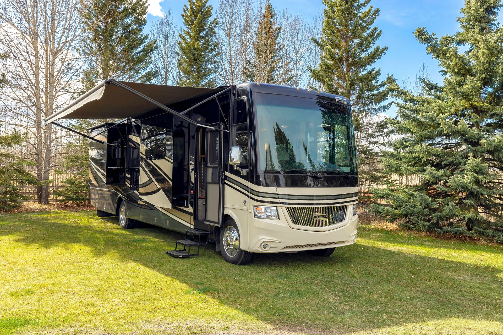 a motor home parked in the grass near some trees