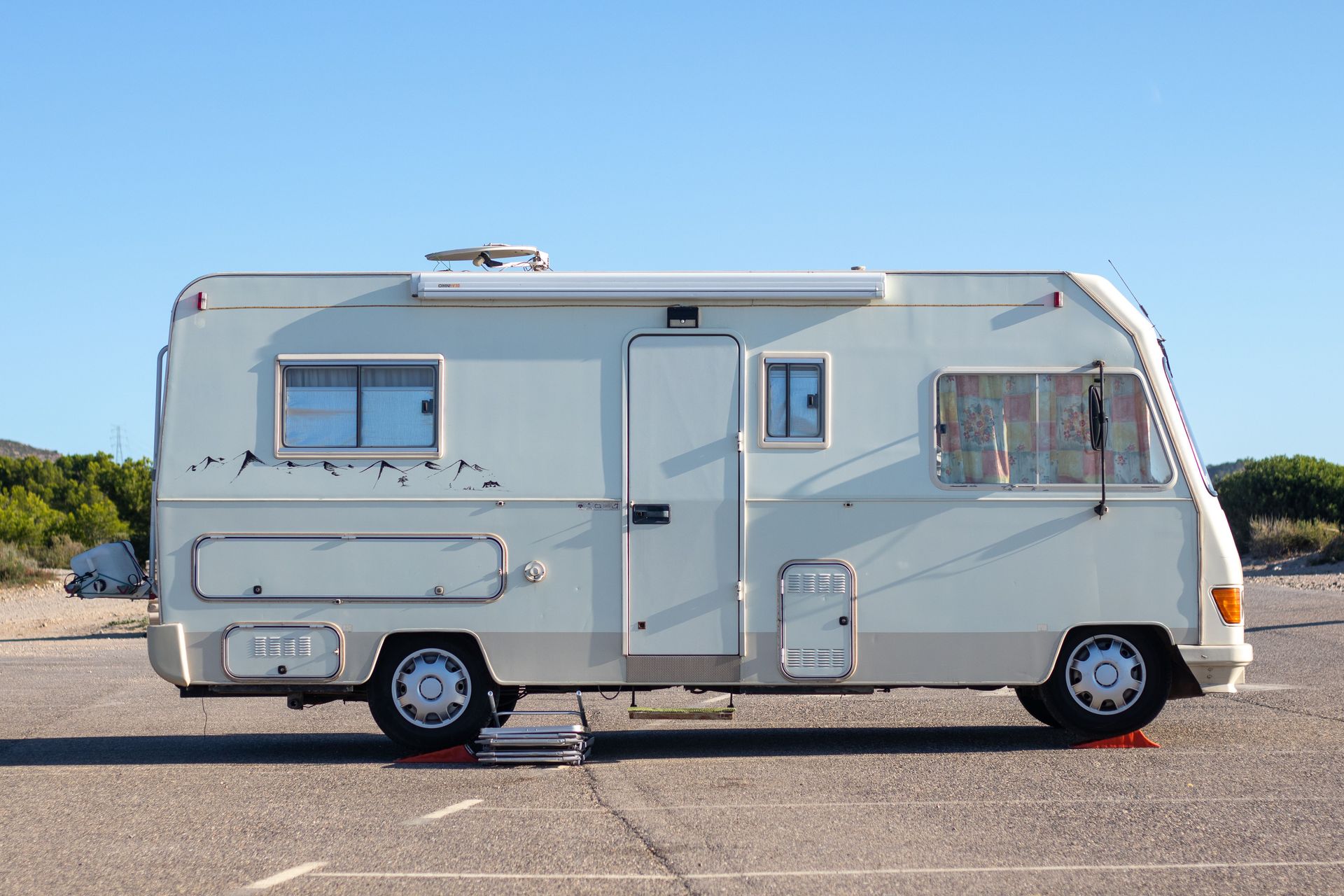 Side view of a vintage camper van parked on an open road under clear blue skies.